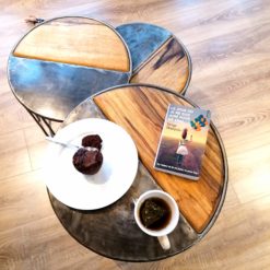 Trois tables gigognes en bois et métal avec un goûter et un livre sur la plus grande table